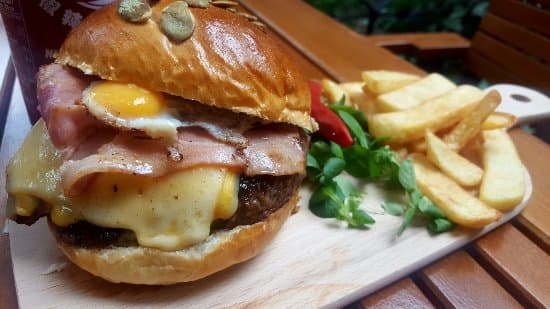 Burger cu ou și bacon, servit pe tocător de lemn